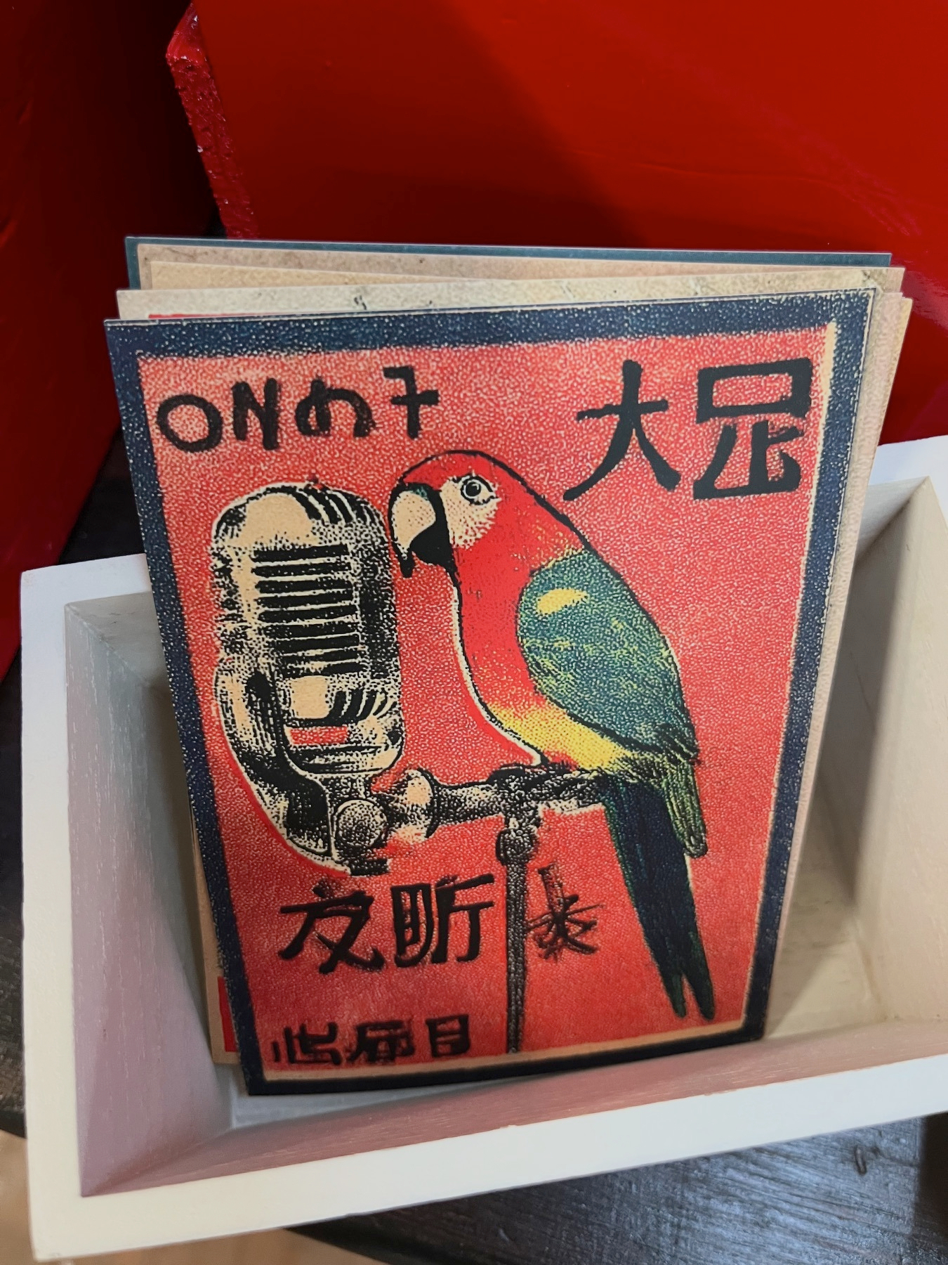 A colorful illustration of a parrot perched on a vintage microphone, surrounded by Chinese characters and stylized text.